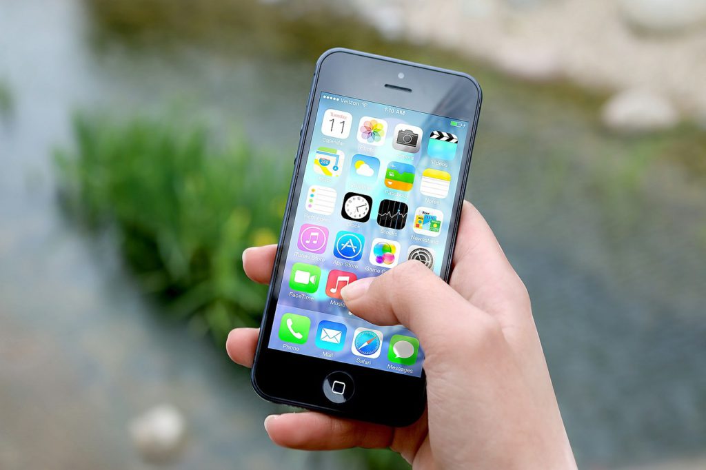 En person håller en smartphone i handen. På skärmen syns flera appar