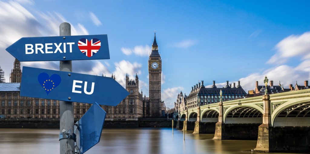 Bild på det kända engelska landmärket Big Ben. I förgrunden syns två skyltar som pekar åt olika håll, de symboliserar Brexit.