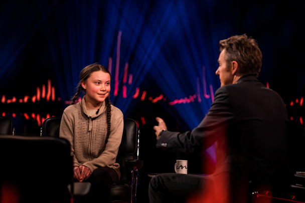 Greta Thunberg ler där hon sitter i en fåtölj i en TV-studio och blir intervjuad av den norska programledaren Fredrik Skavlan.